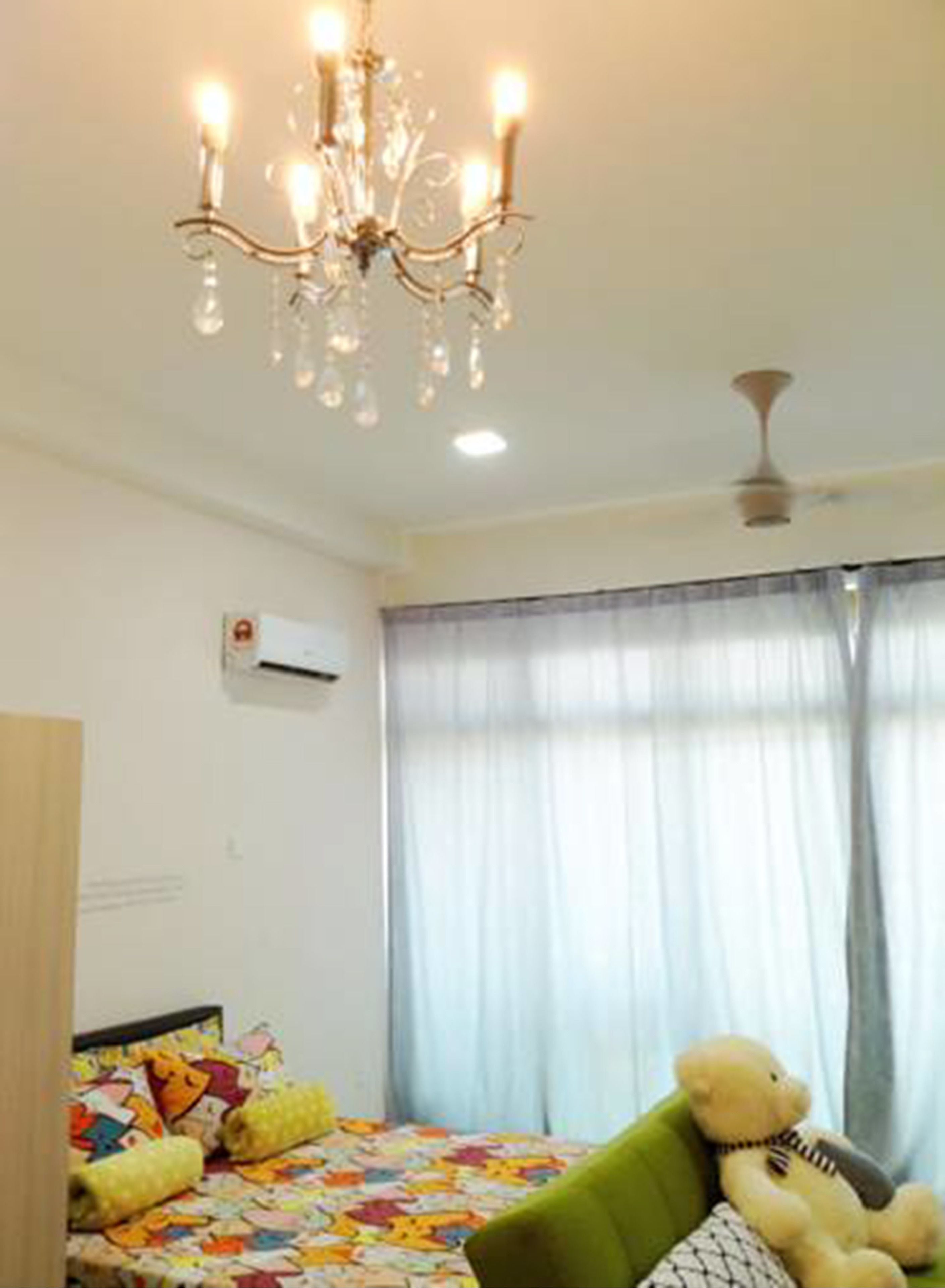 A bedroom with a bed, a teddy bear, a chandelier, and a ceiling fan.