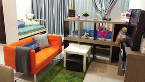 A cozy room with a bed, a small sofa, a coffee table, and a TV. - HomeStay in Johor - Palazio (Johor Bahru)
