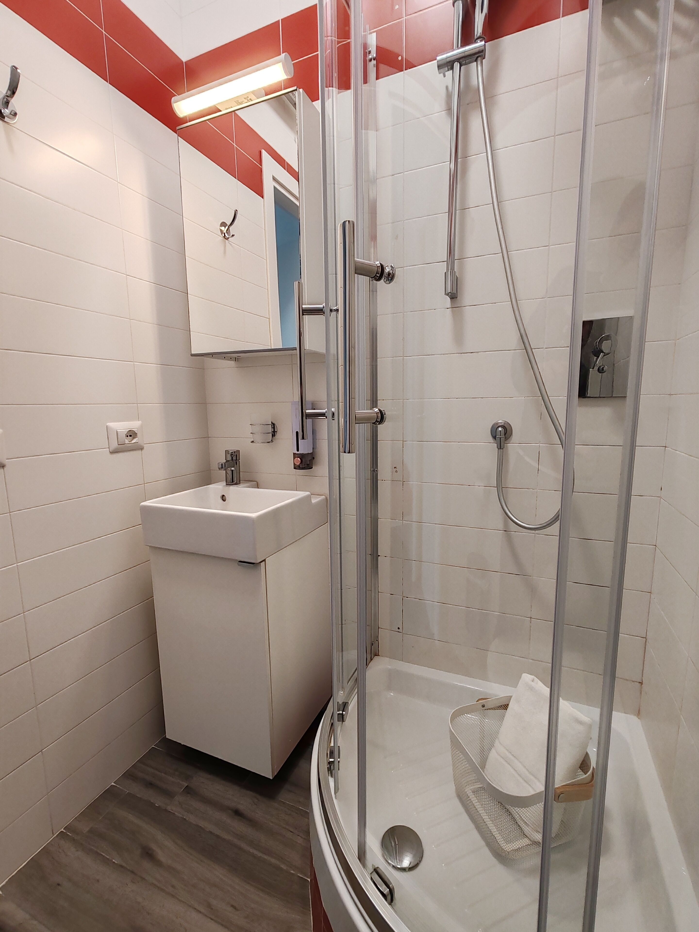A modern bathroom with a glass-enclosed shower, a sink, and a mirror.