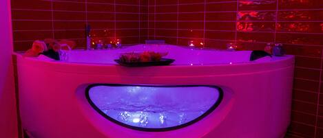 Un jacuzzi dans une pièce aux murs recouverts de carreaux rouges et au plancher en bois.
