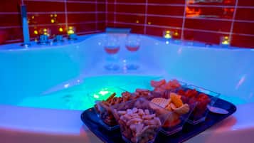 A spa area with a hot tub, clear glass trays of snacks, and a red-tiled wall.