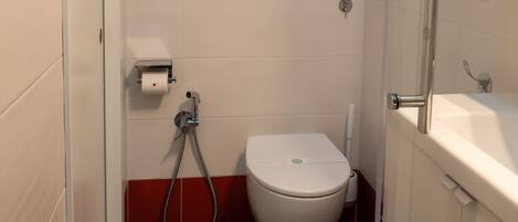 A compact bathroom with a toilet, a shower, and a sink.