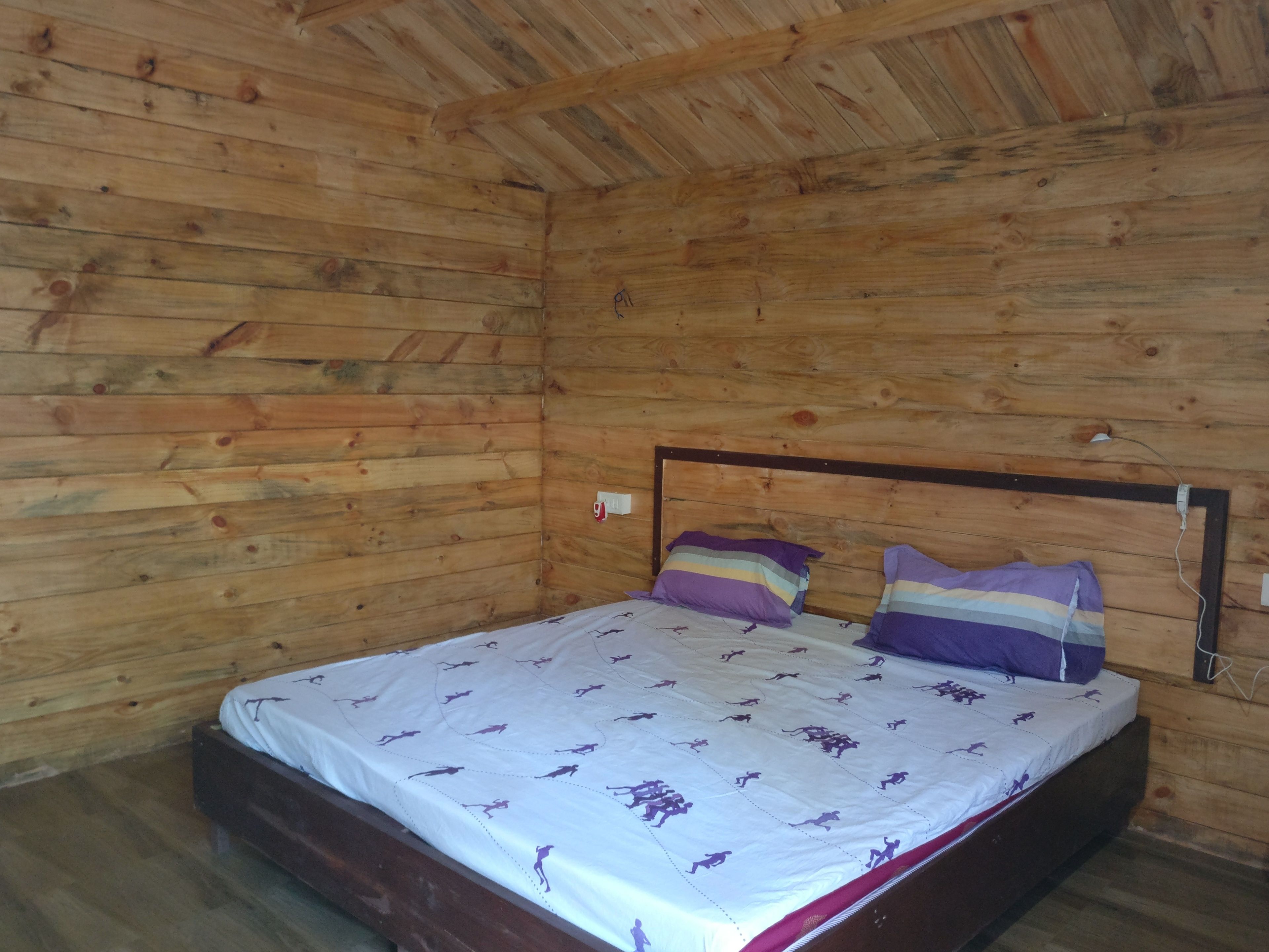 Une pièce de style cabane en bois, avec un lit, des murs en bois et une simple tête de lit.