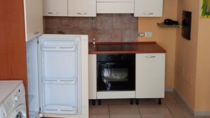 A compact kitchen with white cabinets, a built-in oven, and a washing machine. - Ostello Le Stanze del Sogno (Benevento)