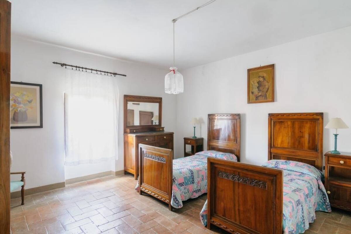 A bedroom with two wooden beds, a dresser, a mirror, and a hanging light fixture.