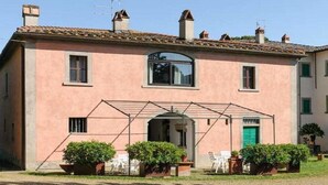 A two-story building with a central entrance, a covered patio area, and a garden with potted plants. - Villa Albergotti (Arezzo)