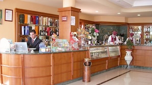Un espace d’accueil d’hôtel avec un comptoir en bois, un ordinateur portable et divers objets exposés.