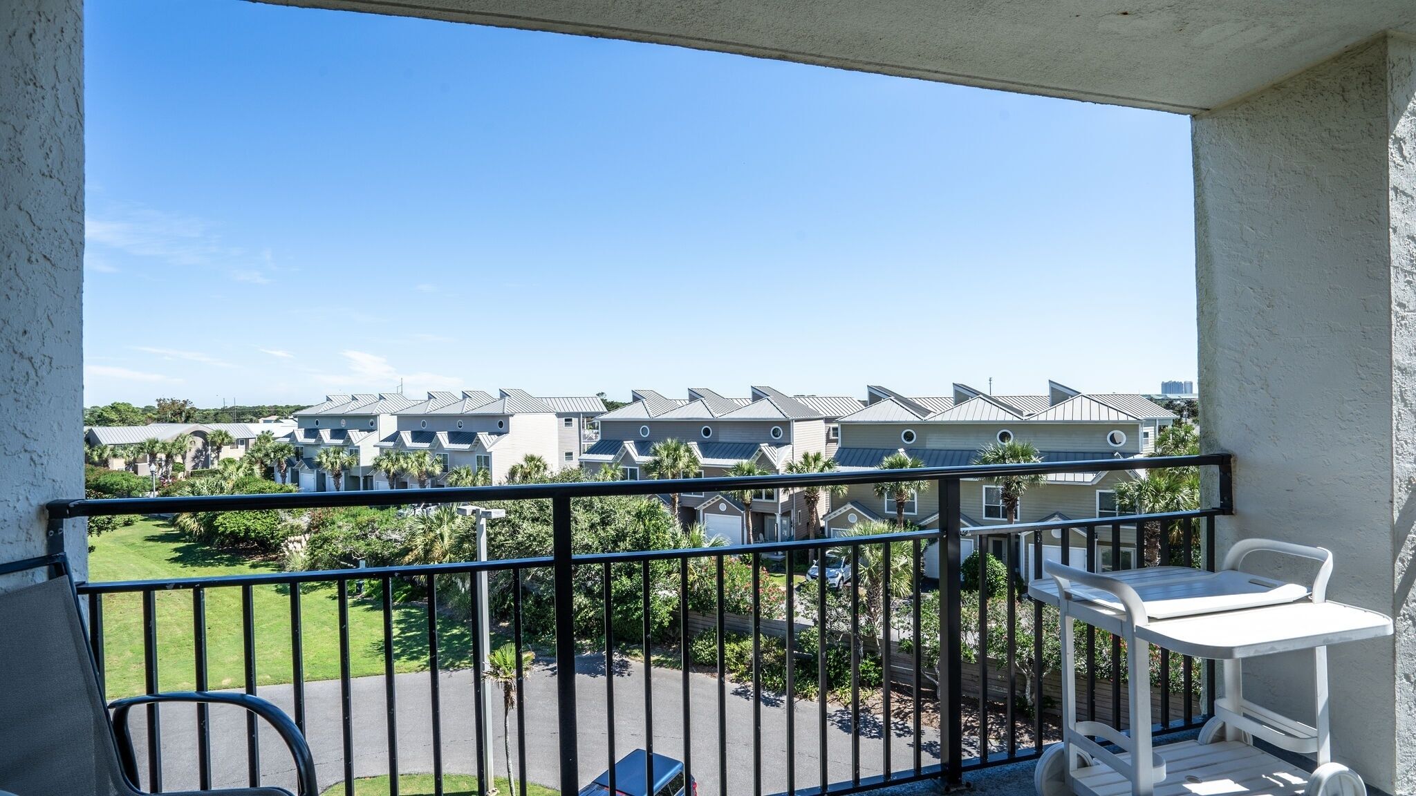 A balcony with a view of a row of modern buildings, a small table, and a chair.