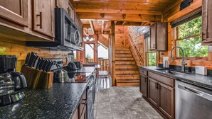 A modern kitchen with wooden cabinets, a stainless steel refrigerator, a microwave, and a coffee maker.