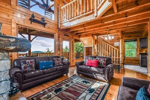 A spacious wooden interior with two sofas, a dining area, and a staircase. - Extravagant View 3 Bedrooms 3 Bathrooms Cabin (Sevierville)