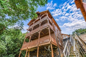 A multi-story wooden building with balconies, surrounded by trees and under a partly cloudy sky. - Extravagant View 3 Bedrooms 3 Bathrooms Cabin (Sevierville)