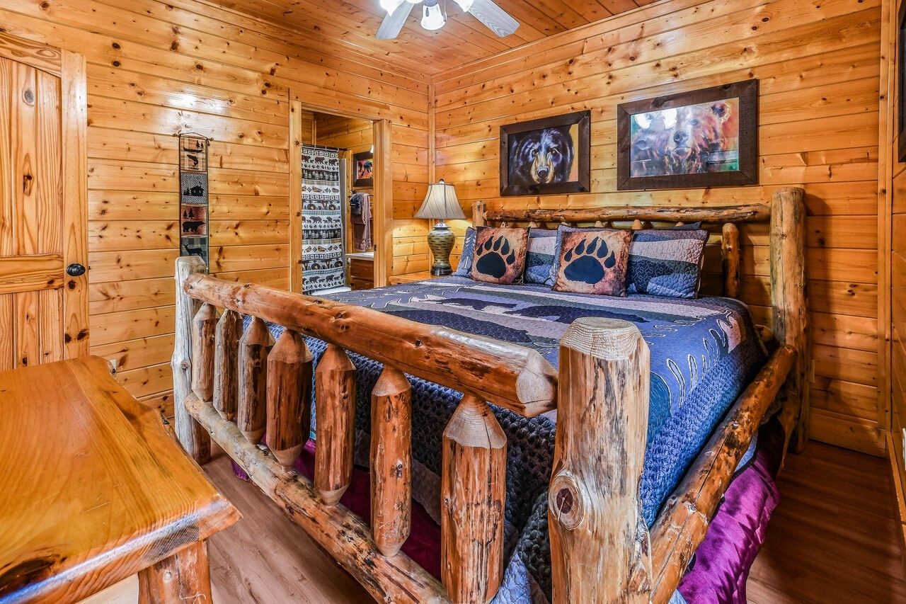 Ein Holzblockhaus-Interieur mit einem Bett, einem Holztisch und einem Deckenventilator.