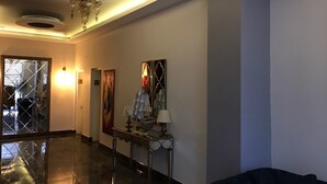 A modern lobby with a polished floor, a chandelier, a decorative table, and a large mirror. - Tum Hotel (Bandirma)