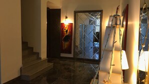 A modern interior with a marble staircase, a glass door with a geometric pattern, and a wall-mounted lamp. - Tum Hotel (Bandirma)