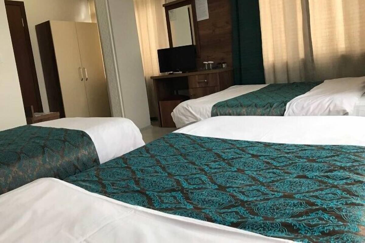 Habitación de hotel con dos camas, televisión, armario y espejo.