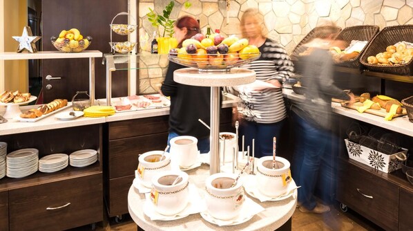 A buffet setup with various food items and beverages, including fruits, pastries, and coffee.