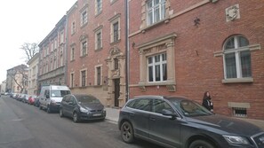 En rad parkerade bilar längs en gata med röda tegelbyggnader.