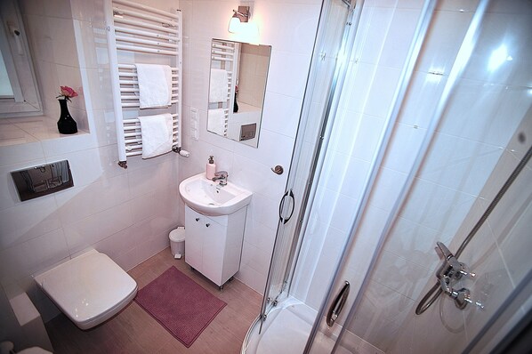 Une salle de bain moderne équipée de toilettes, d’un lavabo et d’une douche à parois en verre.