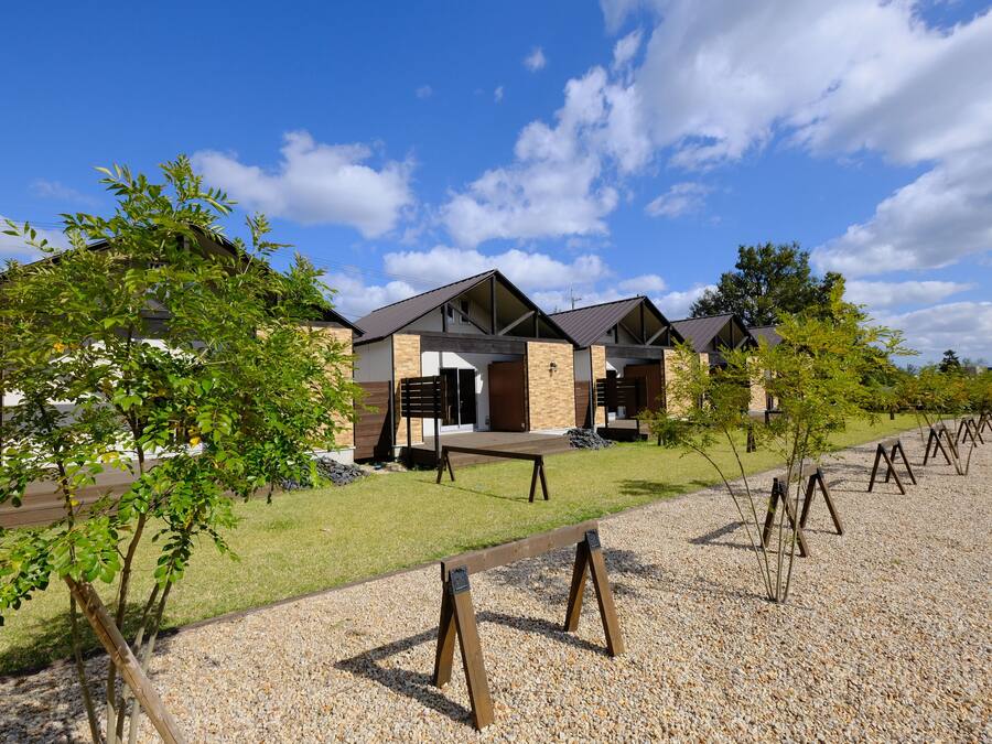 A row of modern houses with a gravel driveway and a grassy lawn.