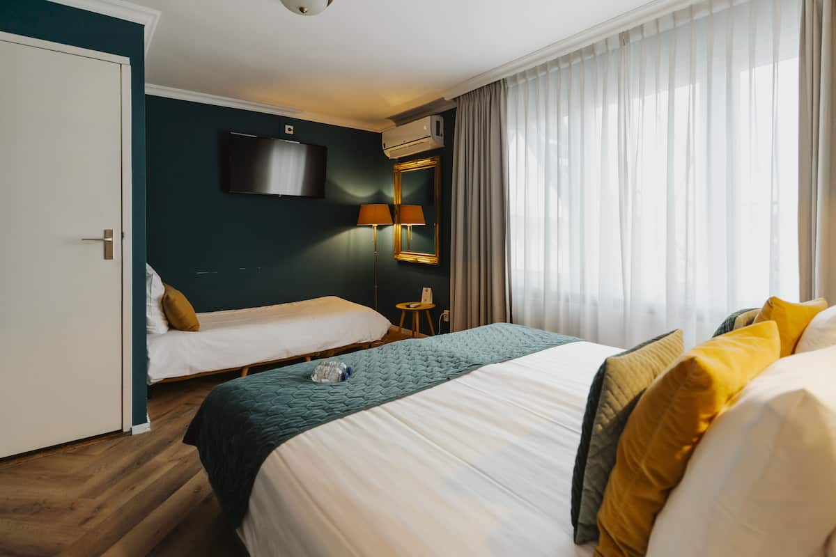 Une chambre d’hôtel avec deux lits, une télévision, un climatiseur et une lampe.