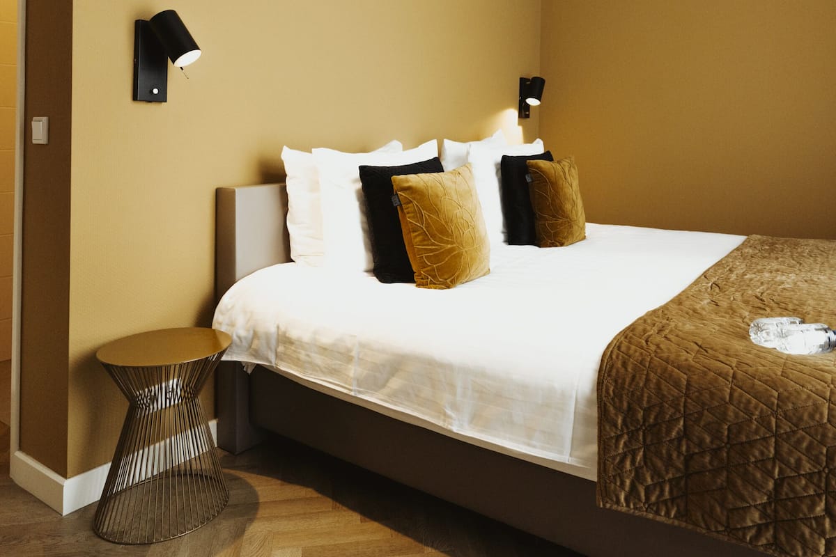 Une chambre à coucher avec un lit, des tables de chevet et une lampe fixée au mur.