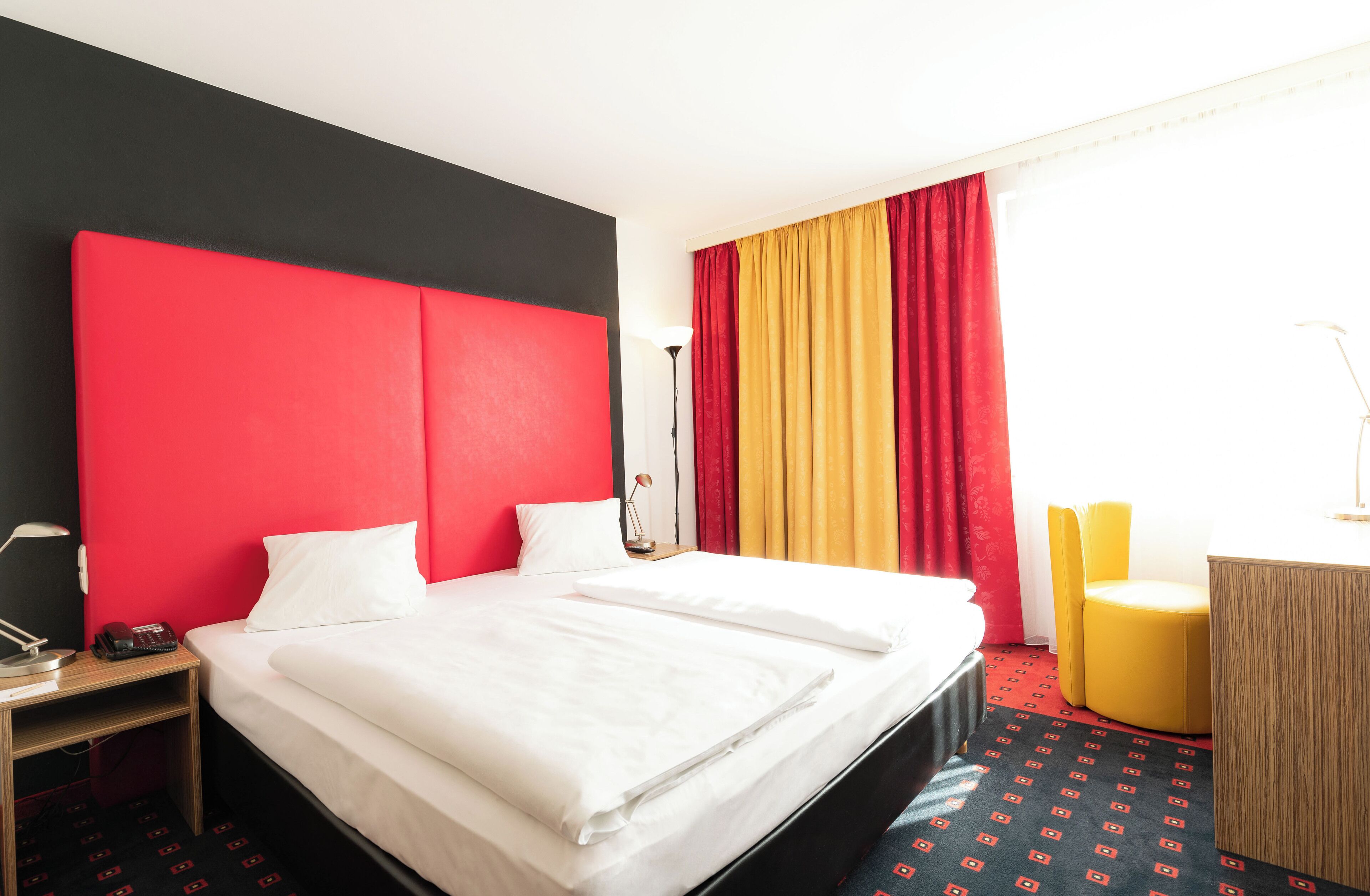 Habitación de hotel con una cama grande, un escritorio, una silla y una ventana con cortinas.