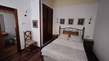 A bedroom with a bed, a chair, a wardrobe, and a small bedside table.