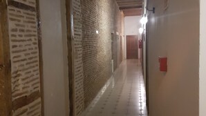 Un pasillo con suelo de baldosas, paredes de ladrillo y vigas de madera en el techo.