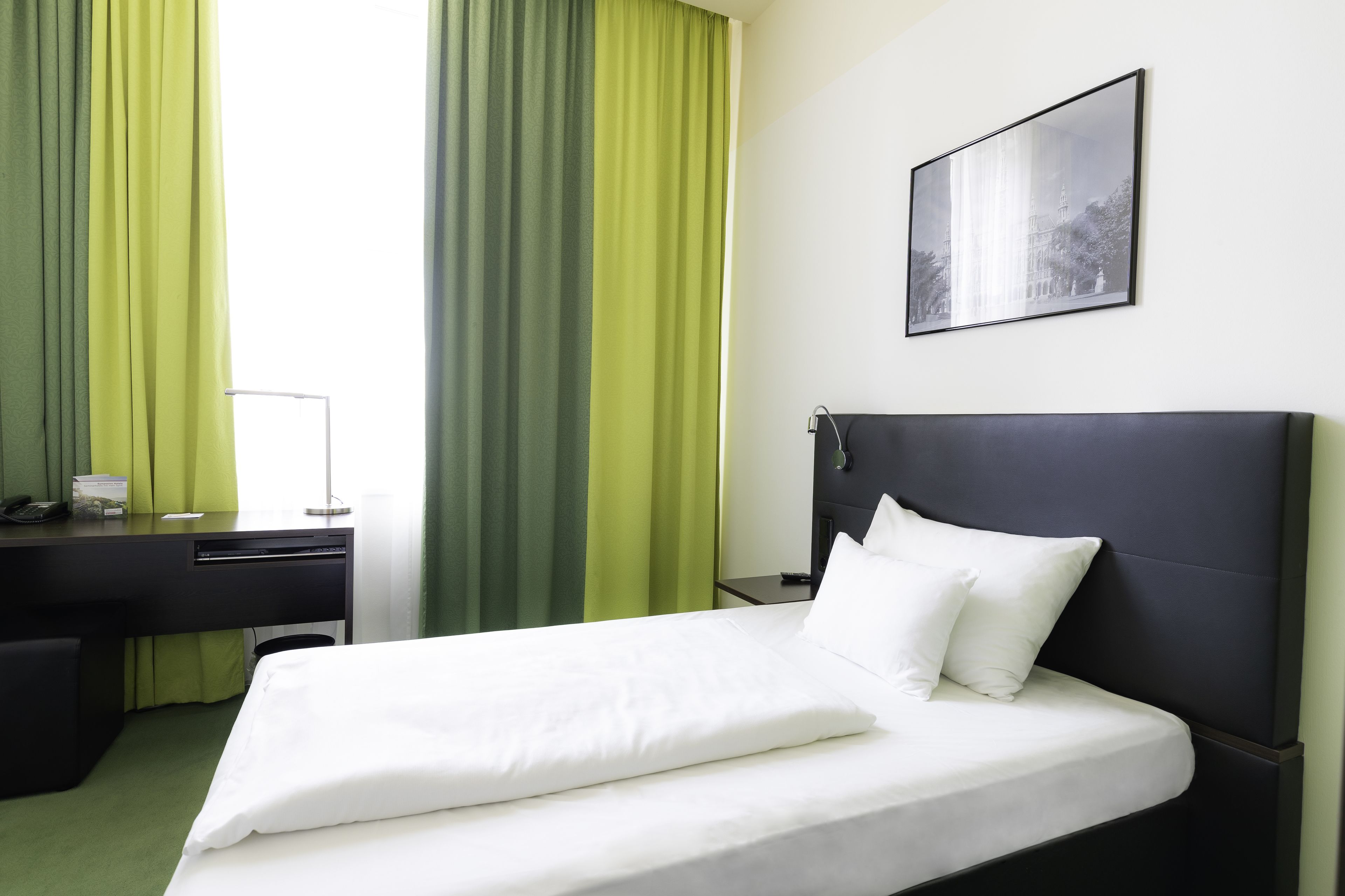 A hotel room with a bed, a desk, and a chair.