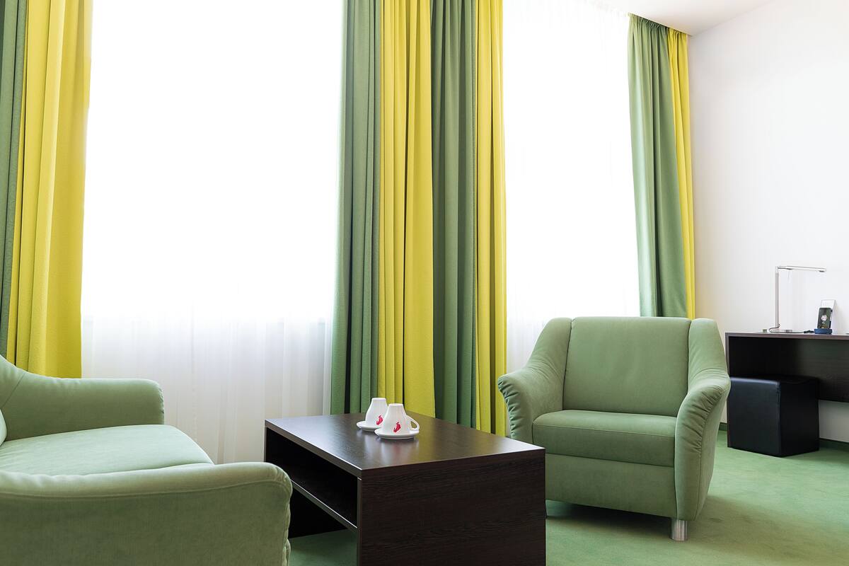A room with two green armchairs, a dark wooden coffee table, and a small black side table.