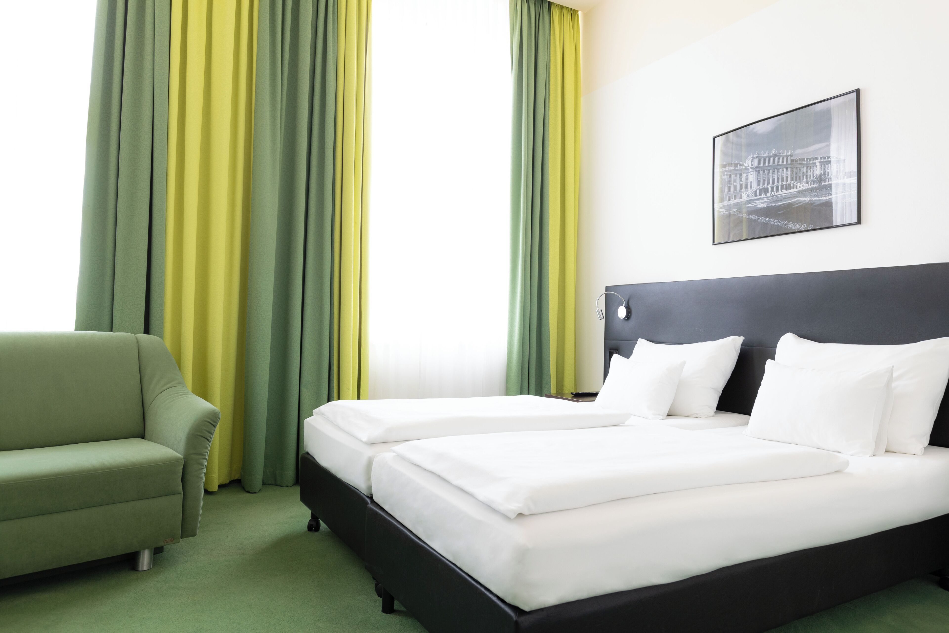 A hotel room with a bed, a sofa, and curtains.