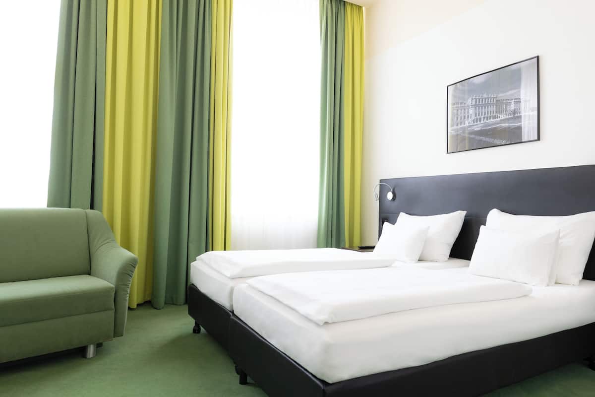 Ein Hotelzimmer mit Bett, Sofa und Vorhängen.