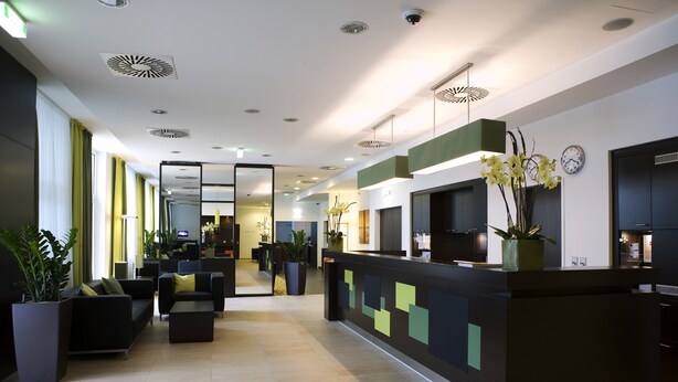 Eine moderne Lobby mit einer Rezeption, einer Sitzecke und großen Fenstern.