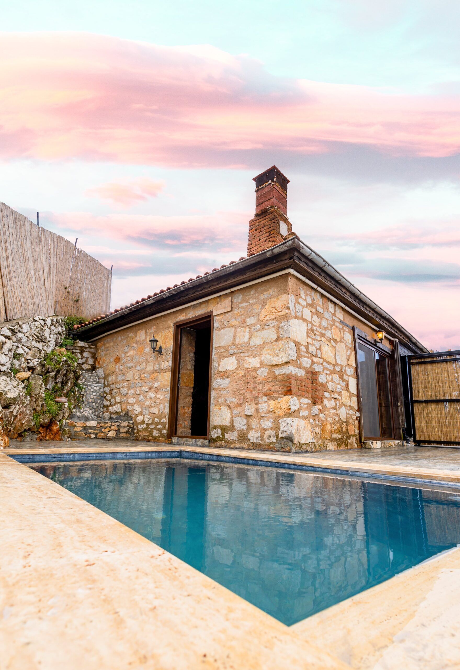 Un bâtiment en pierre doté d’une piscine, d’une cheminée et d’une clôture en bois.