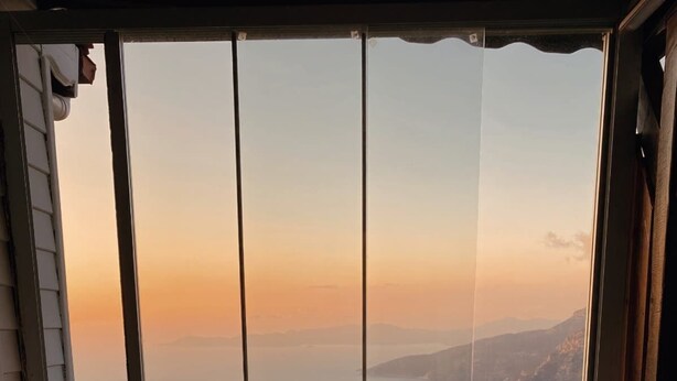 Uma pessoa relaxando em uma banheira de hidromassagem com vista panorâmica de montanhas e um corpo d'água.