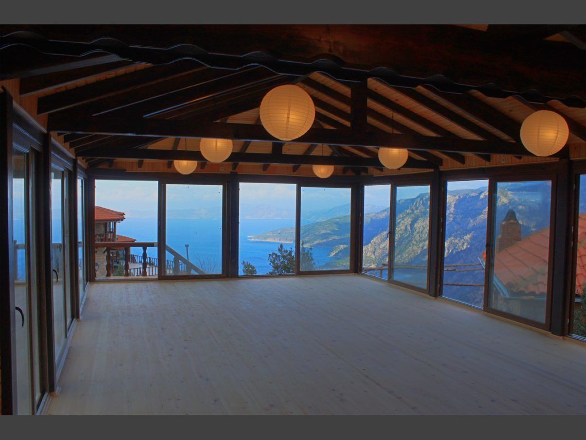 A spacious room with large windows offering a view of the sea and mountains.