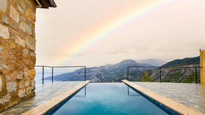 Piscina com vista para montanhas e um arco-íris.