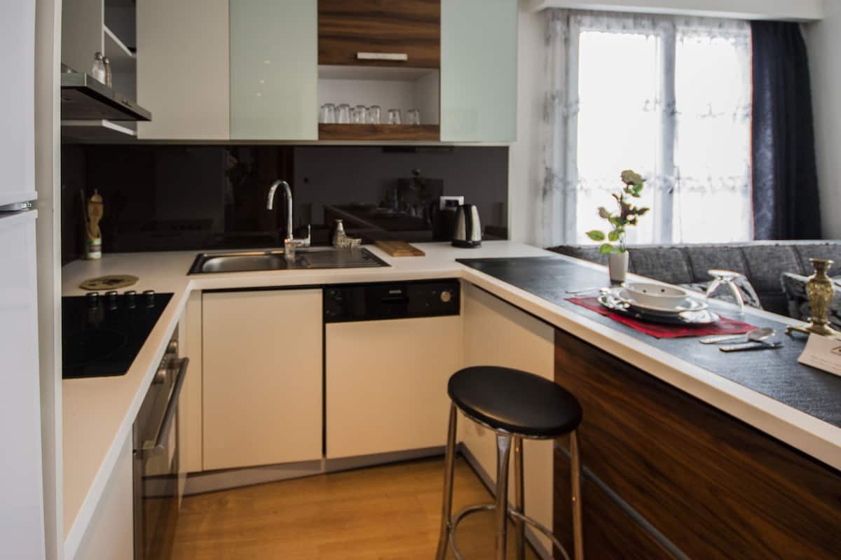 A compact kitchen with a dishwasher, a sink, and a bar stool.