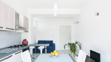 Een moderne keuken met een eethoek, een blauwe bank en een televisie.