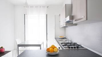 A modern kitchen with a gas stove, white cabinets, and a dining area with a glass table and chairs.