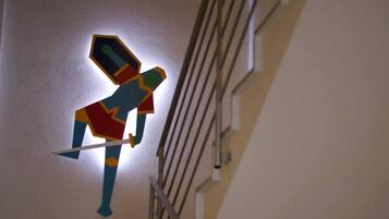 Een geometrisch kunstwerk aan de muur, waarop een figuur een zwaard vasthoudt.