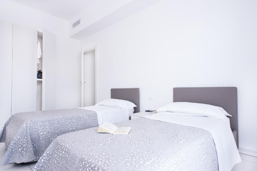 A hotel room with two beds, a wardrobe, and a book on the bed.