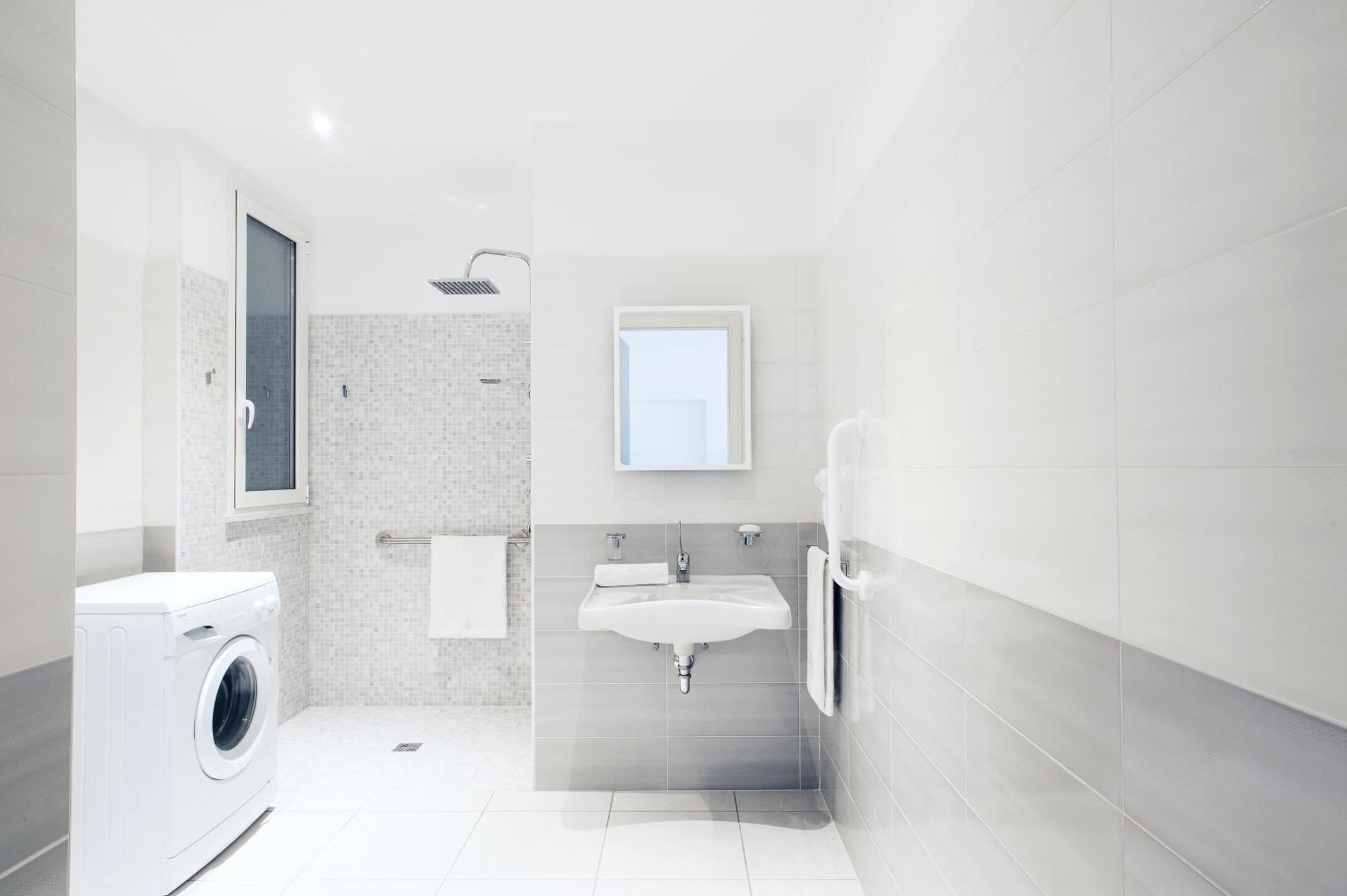 Un baño moderno con lavadora, lavamanos y ducha.