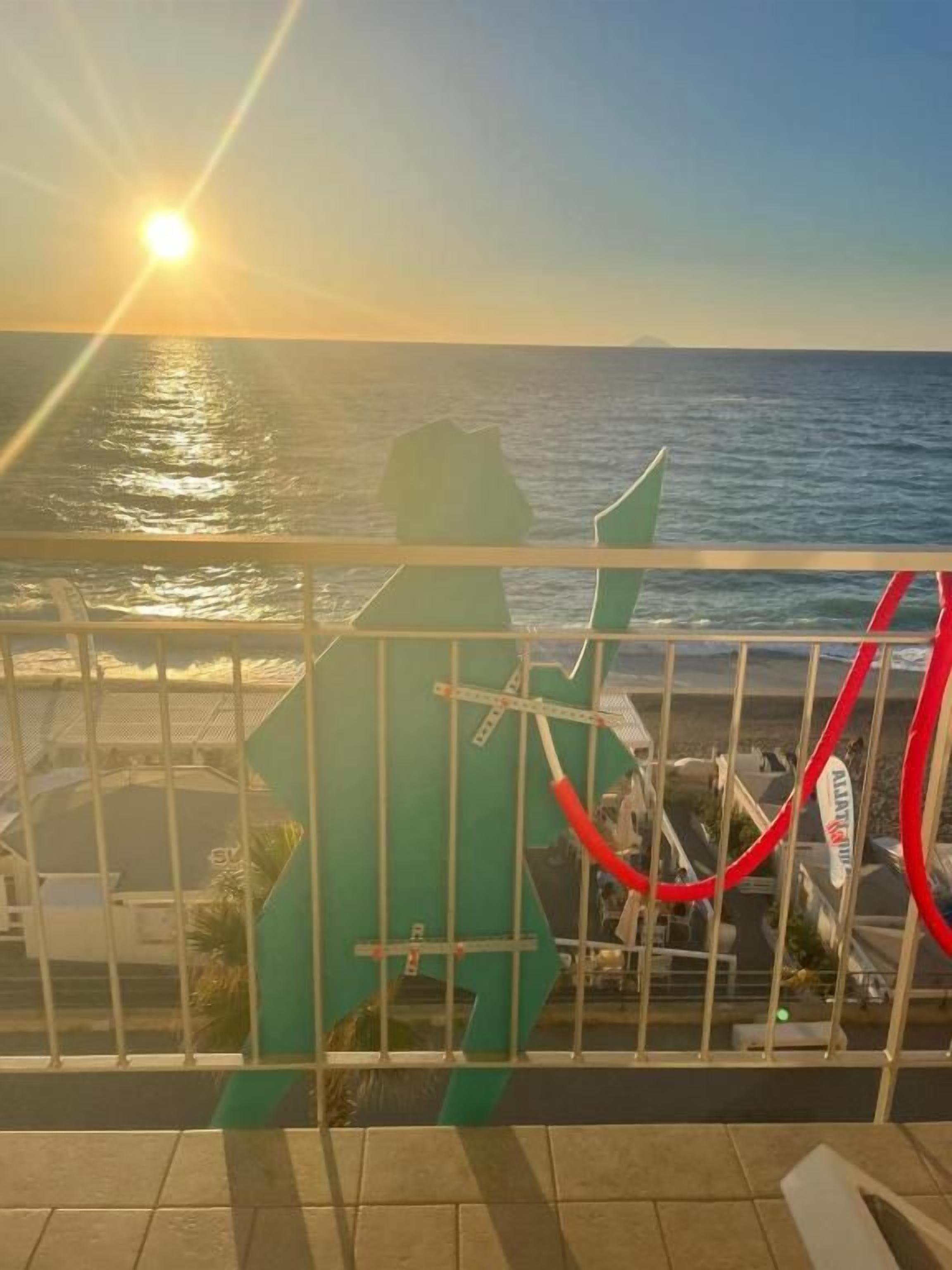 A balcony with a view of the sea during sunset.