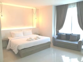 Una habitación de hotel moderna con una cama grande, un sofá y una ventana con cortinas.