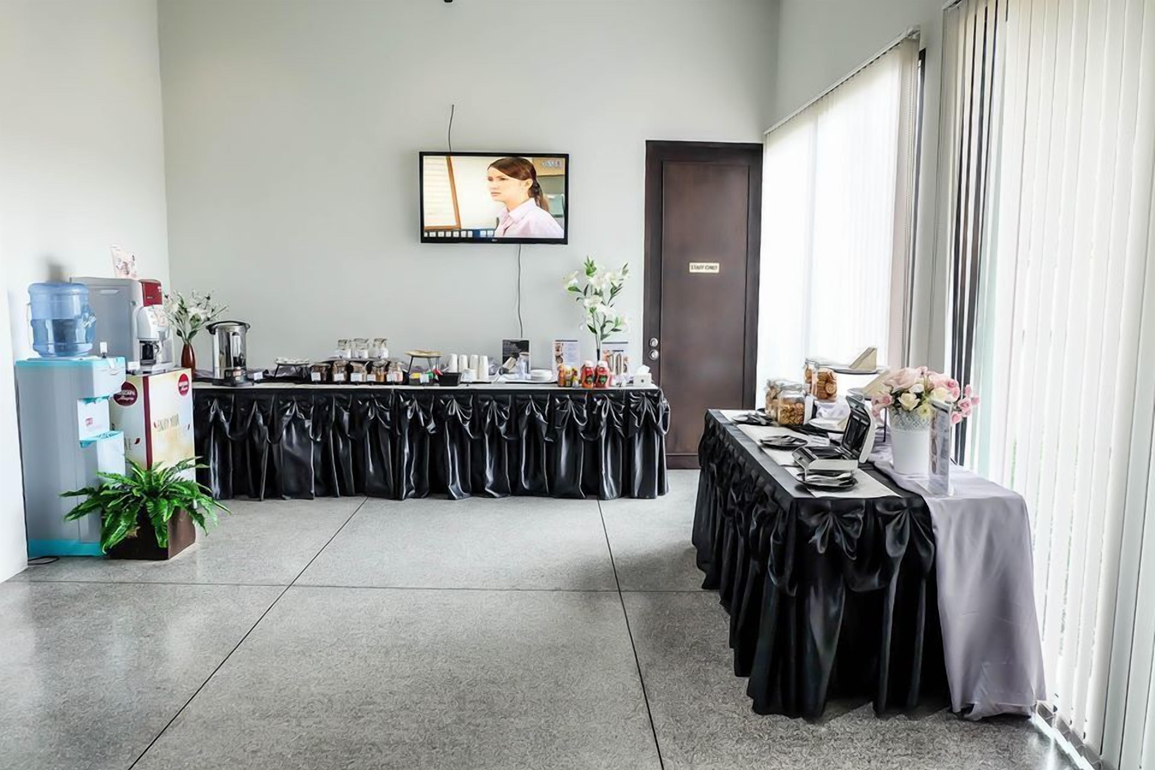 Un salón de conferencias con una larga mesa, un dispensador de agua y una pantalla de televisión.