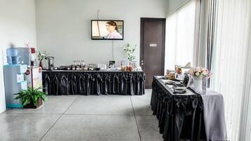Un salón de conferencias con una larga mesa, un dispensador de agua y una pantalla de televisión.
