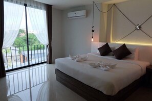 Habitación de hotel con una cama grande, vistas a zonas verdes, aire acondicionado y una lámpara moderna.