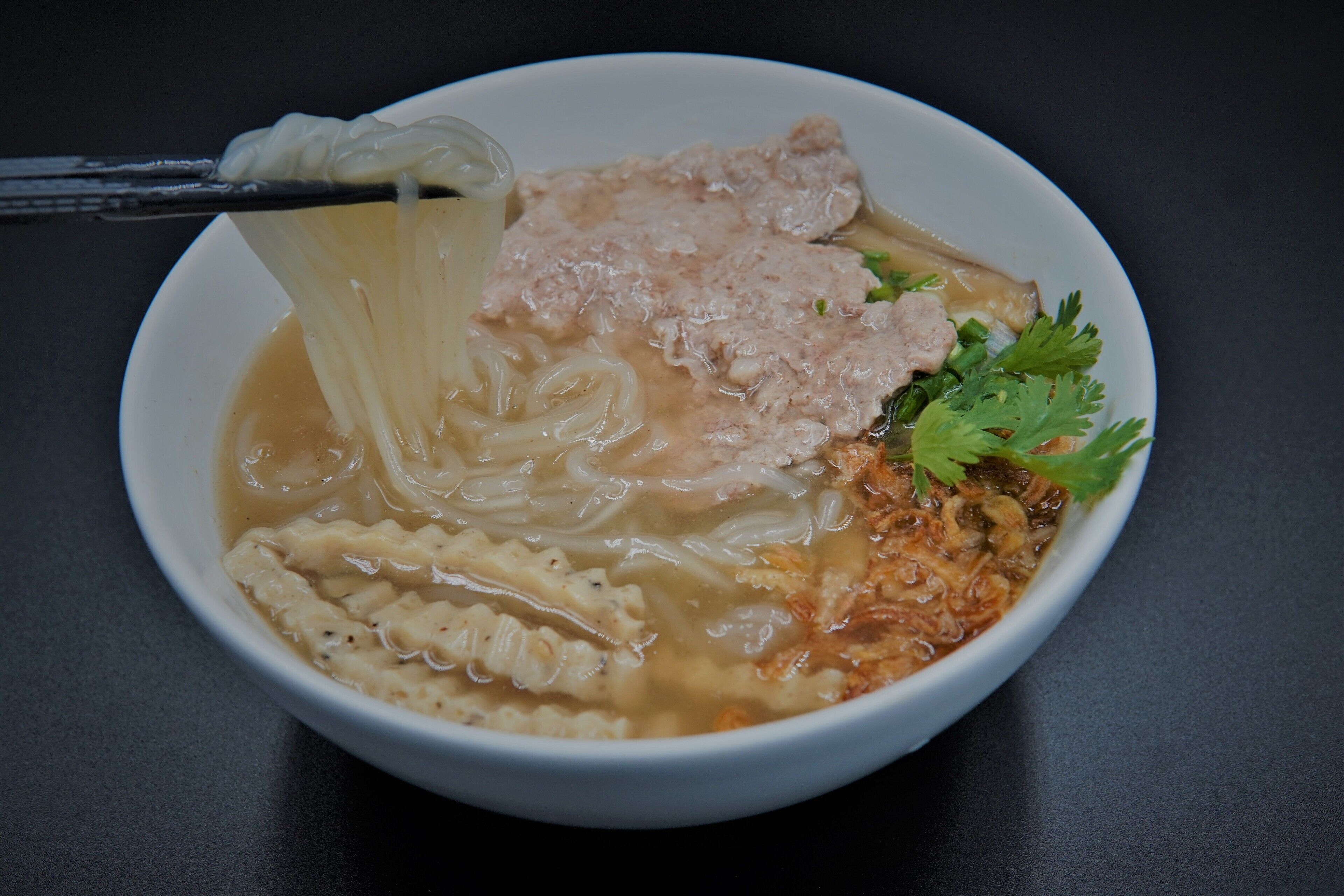 A bowl of ramen with noodles, meat, and vegetables.