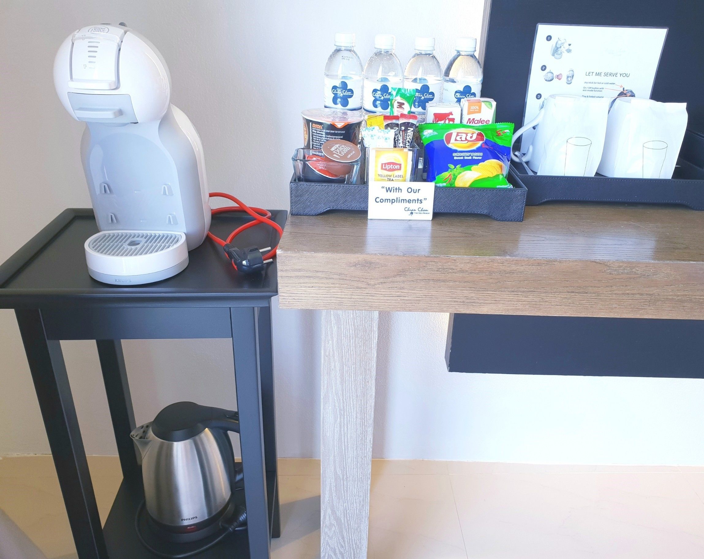 Een koffieapparaat, een waterkoker en een waterdispenser op een tafel met een bord waarop staat: 'Met onze Complimenten'.